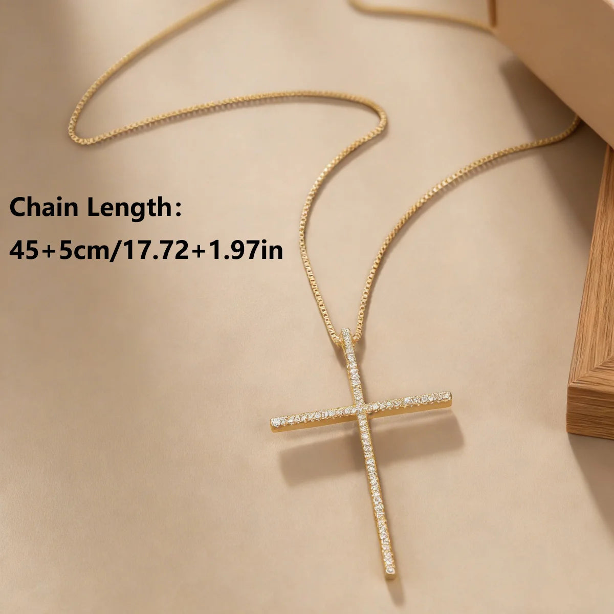A gold cross pendant necklace with small clear stones on the cross, shown on a beige surface with text indicating a chain length of 45+5cm (17.72+1.