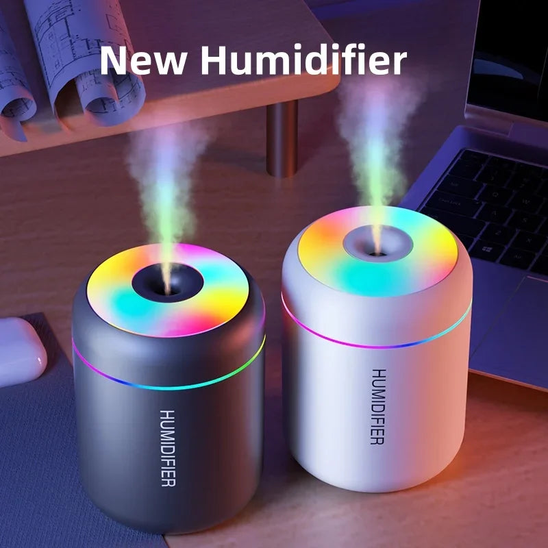 Two colorful humidifiers on a desk with a laptop and mouse in the background.