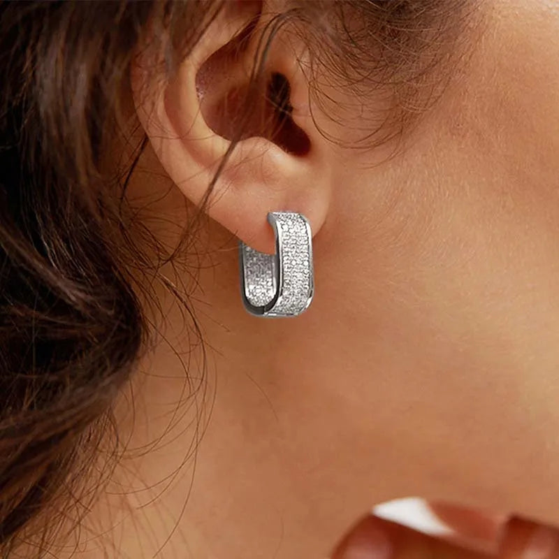 Silver hoop earring worn by a person with brown hair.