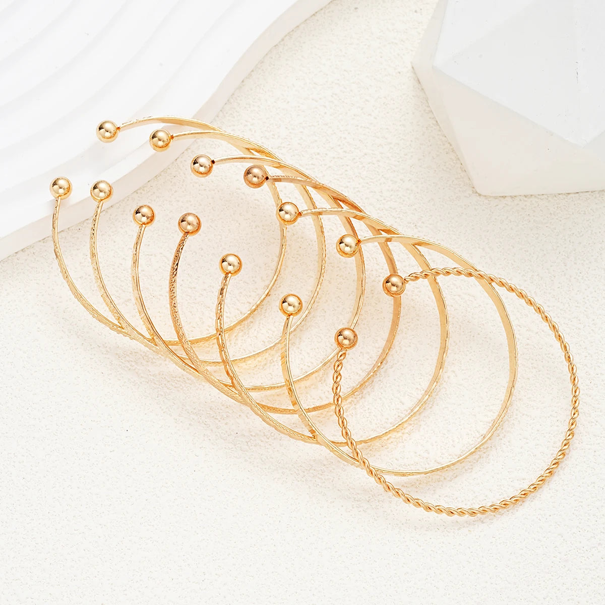 Set of gold bracelets on a white surface