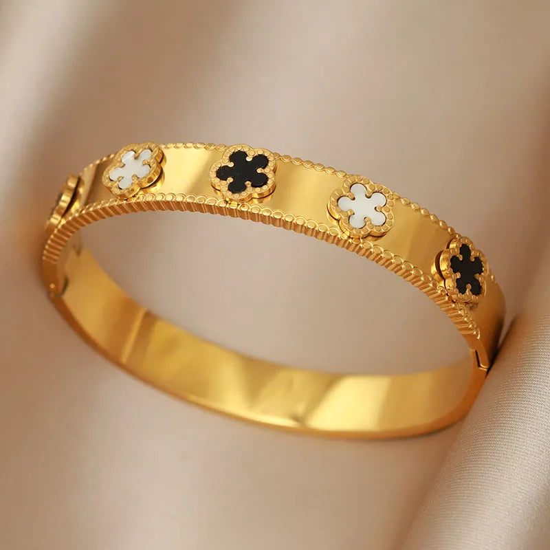 Gold bracelet with clover-shaped charms on a beige background