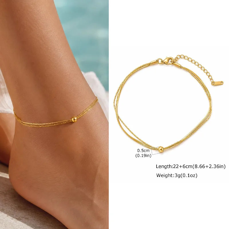 Gold anklet on a foot with product details on a white background