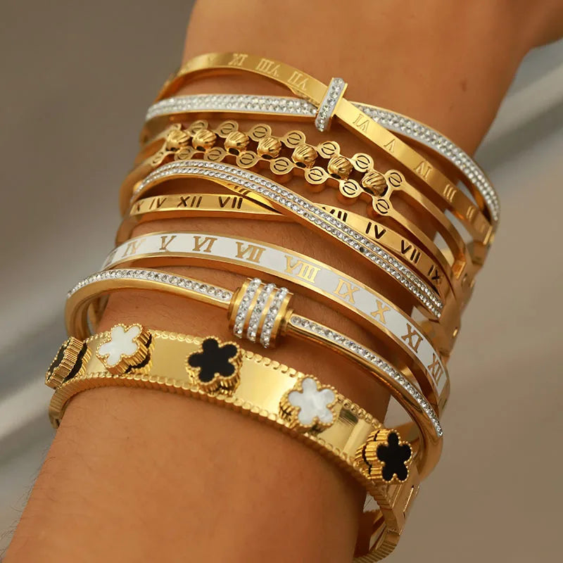 Multiple gold and silver bracelets on a wrist with a neutral background