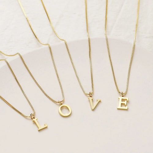 Gold necklaces with 'LOVE' letter pendants on a light background