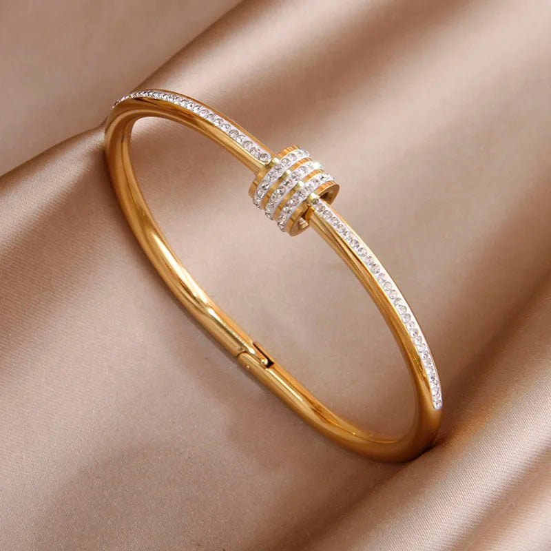 Gold bracelet with diamond accents on a beige fabric background