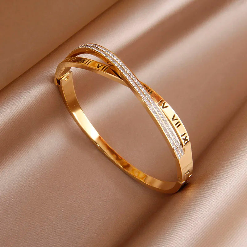 Gold bracelet with Roman numeral design on a beige fabric background