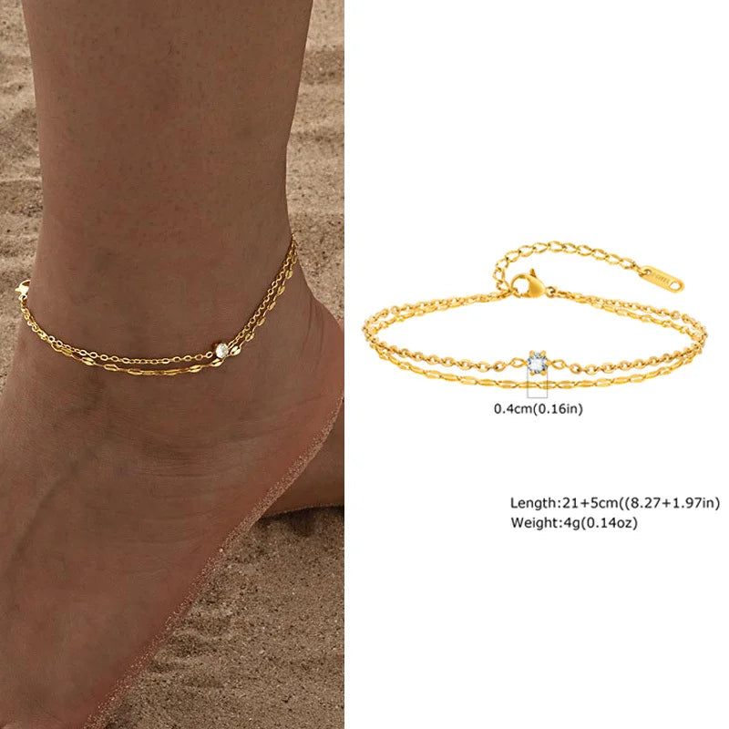Gold anklet on a foot with product details on a white background