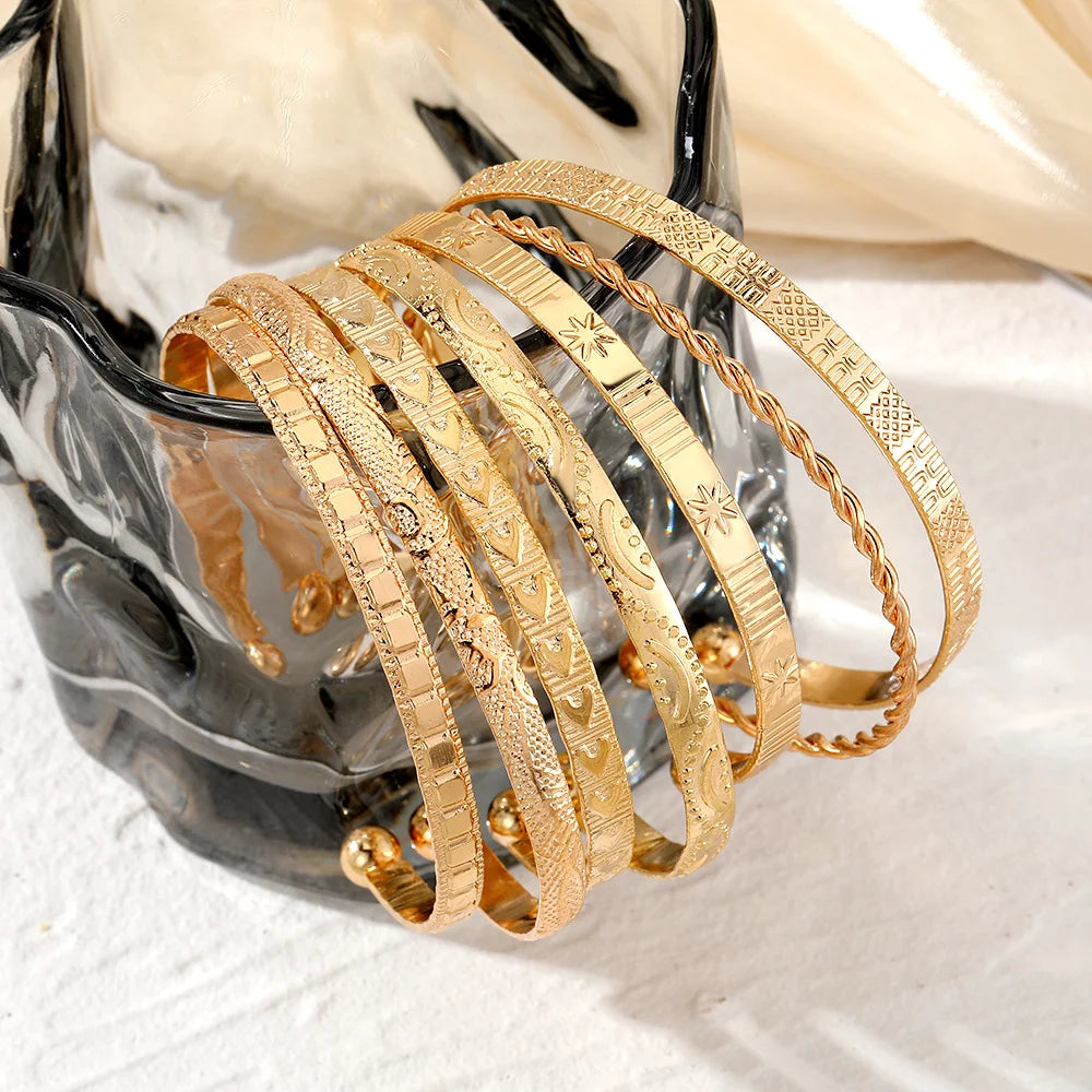 Set of gold bracelets on a decorative stand with a marble background