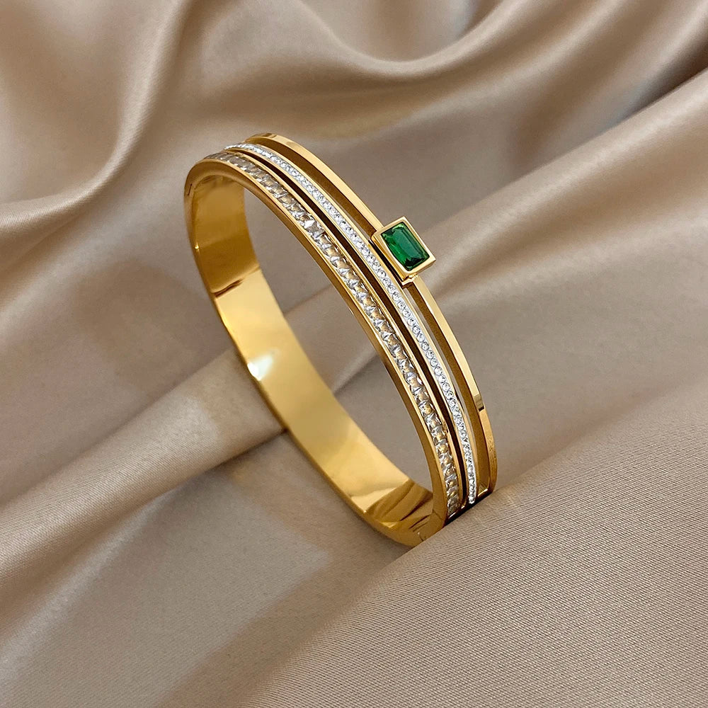 Gold bracelet with a green gemstone on a beige fabric background