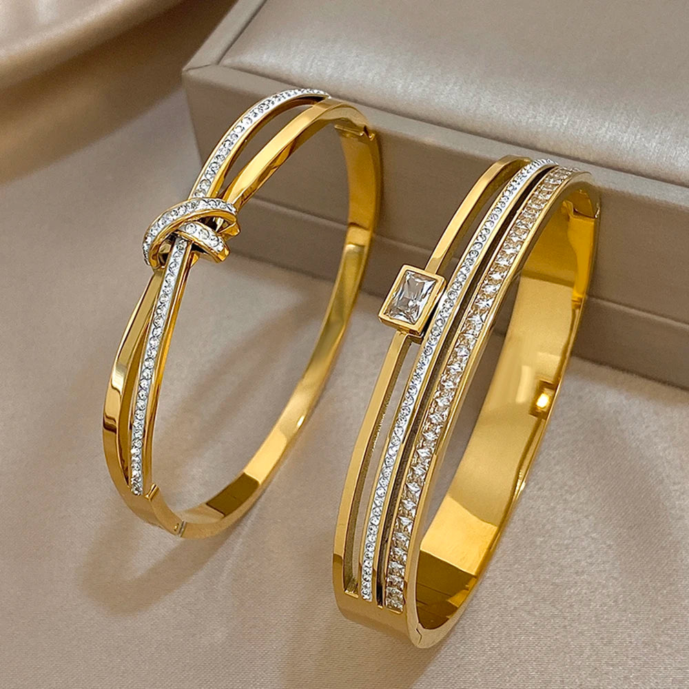 Two gold bracelets with diamond accents on a beige surface