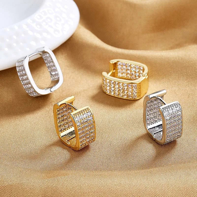 Gold and silver hoop earrings on a beige fabric background