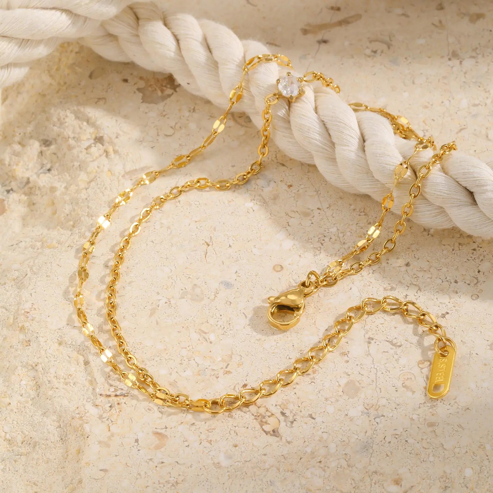 Gold chain necklace on a textured beige surface
