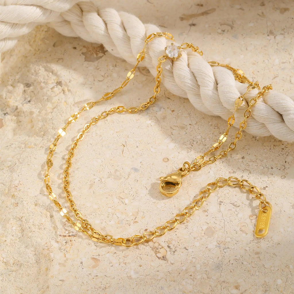 Gold chain necklace on a textured beige surface