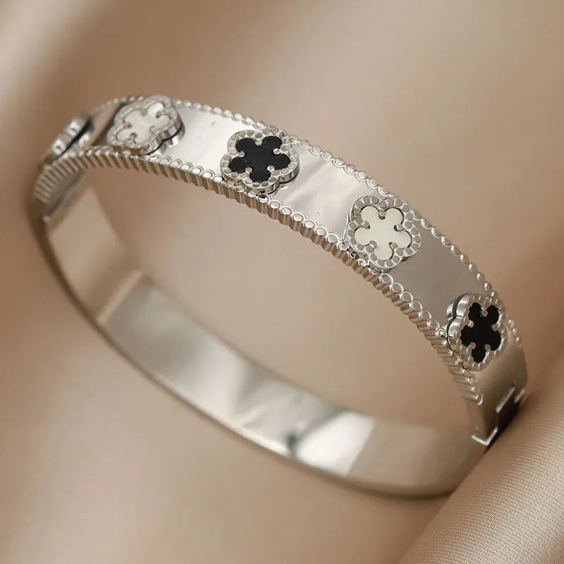 Silver bracelet with clover designs on a beige background
