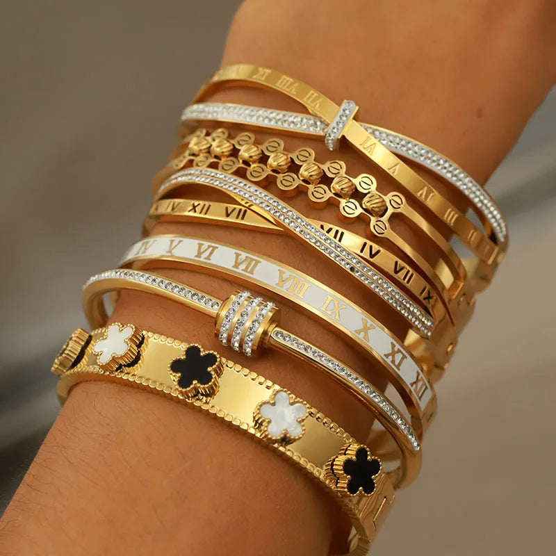 Gold and silver bracelets on a wrist against a neutral background
