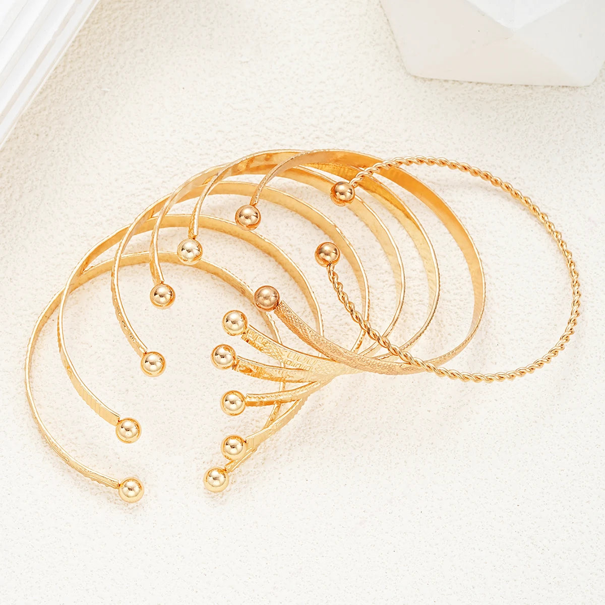 Set of gold bangles on a light beige fabric background