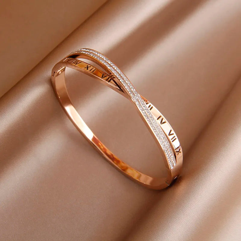 Rose gold bracelet with Roman numeral design on a beige fabric background