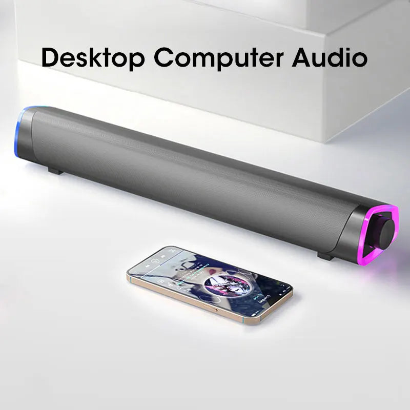 Long cylindrical speaker with pink accents on a white surface, next to a smartphone displaying music app.