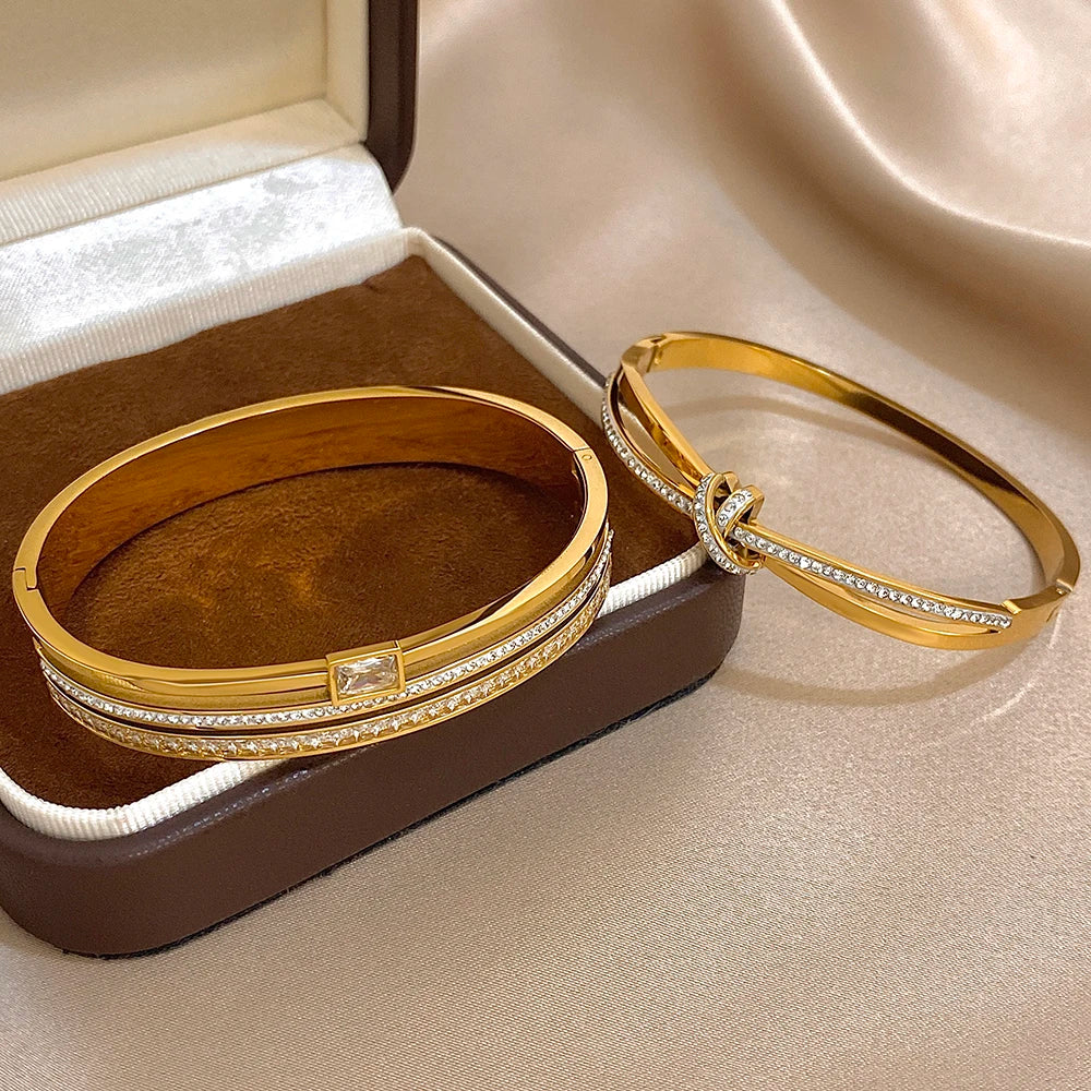Gold bangles with diamond accents on a brown jewelry box.