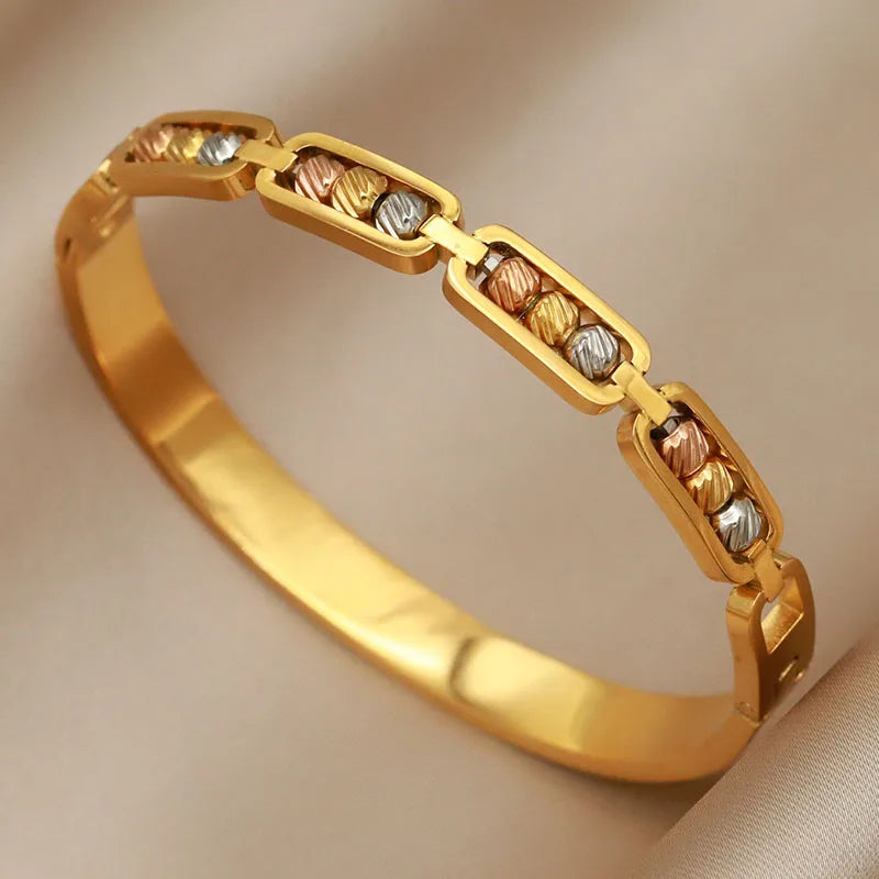 Gold bracelet with interlocking links on a beige background