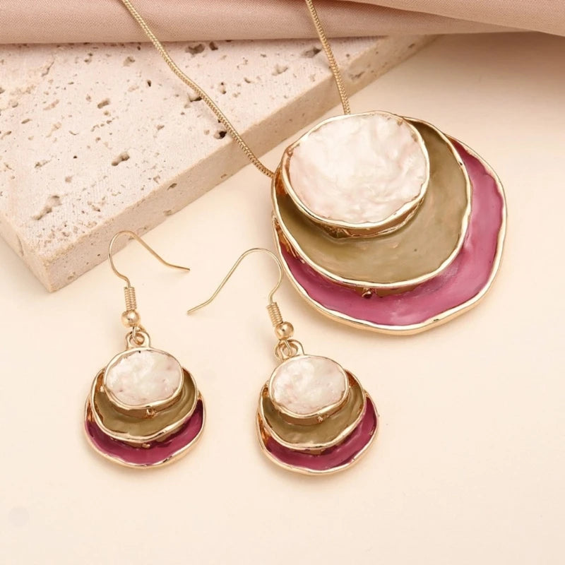 Jewelry set with circular earrings and necklace on a textured surface