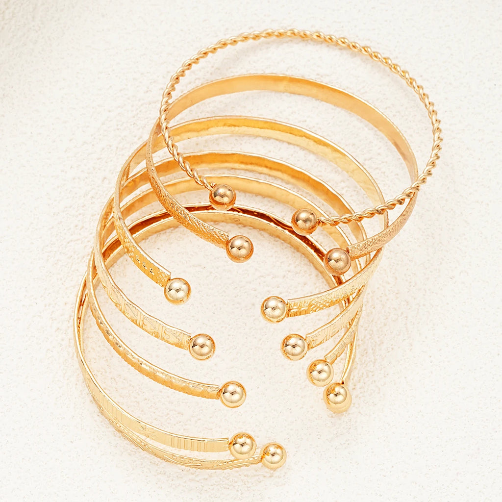 Set of gold bracelets on a textured beige surface