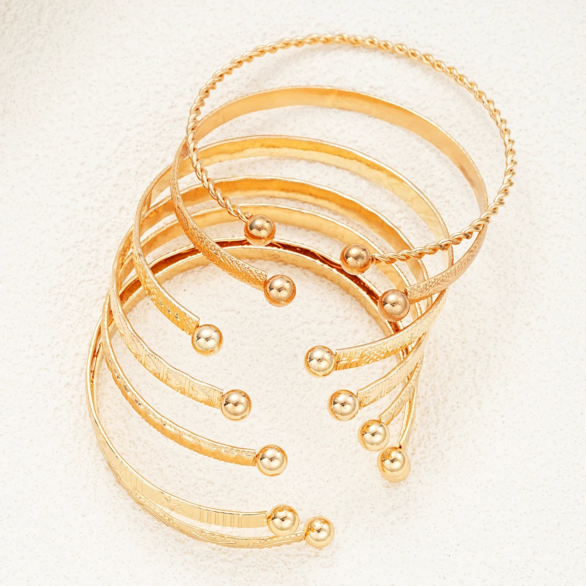 Set of gold bracelets on a textured beige surface