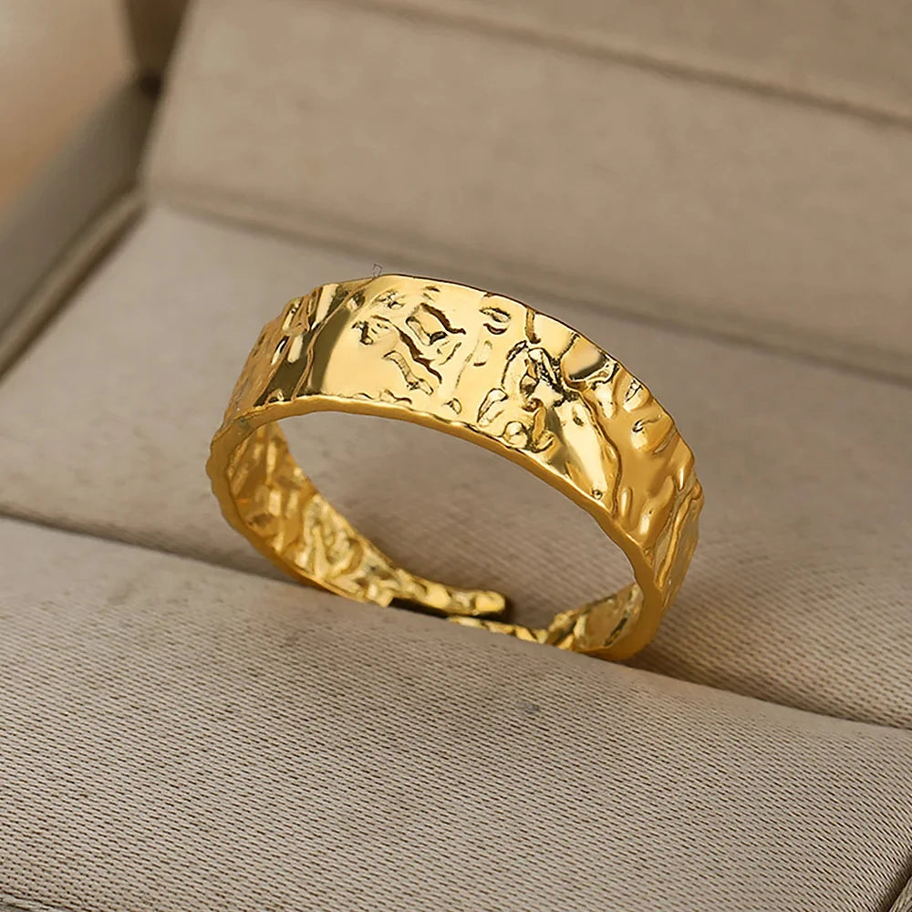 Gold ring with textured design on a beige fabric background
